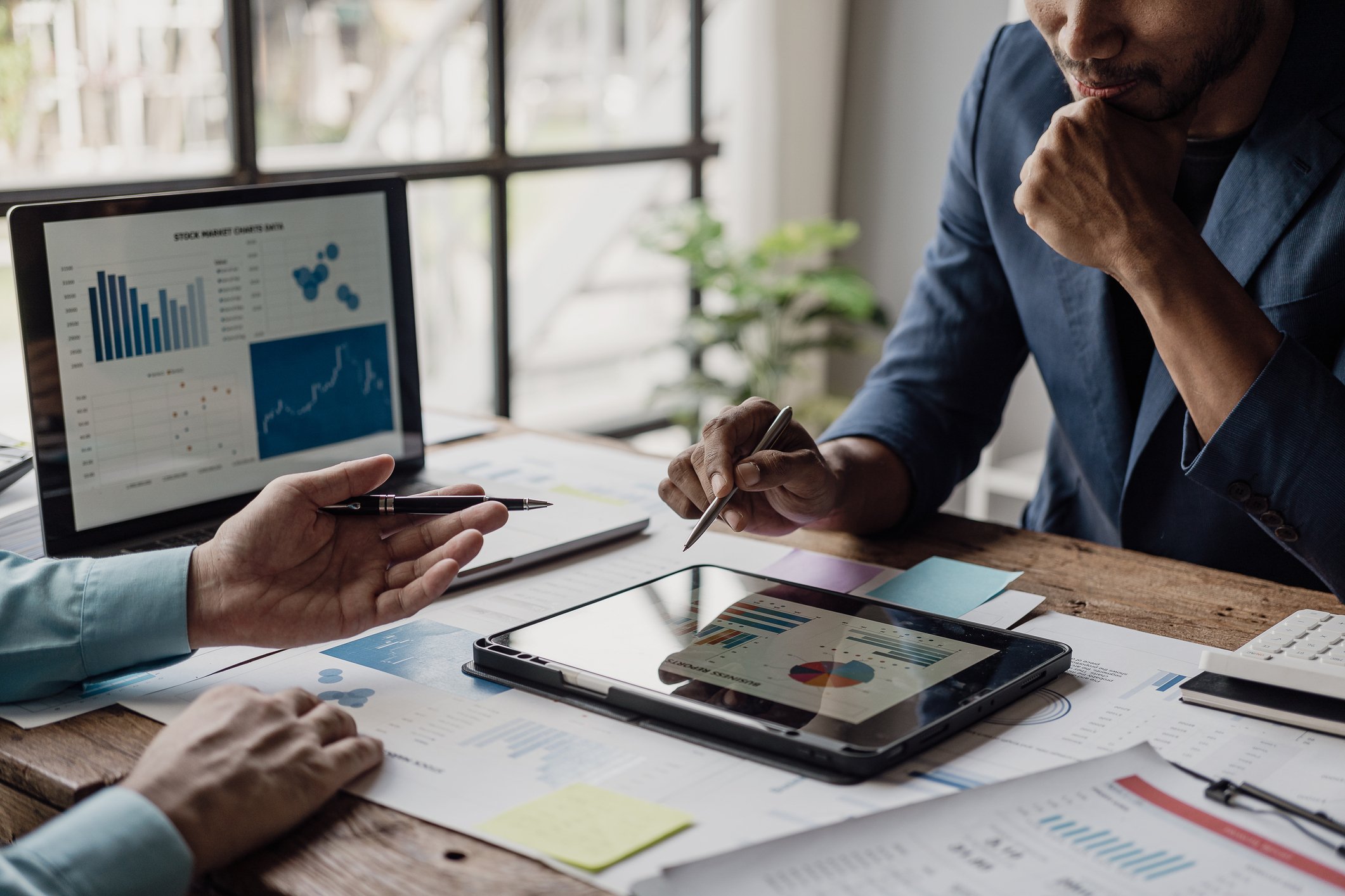 A group of smart young businessmen come together to analyze financial data graphs