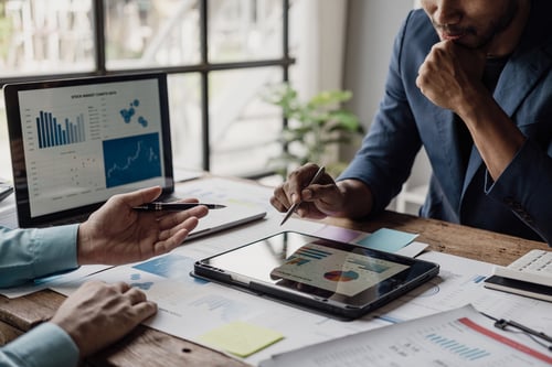 A group of smart young businessmen come together to analyze financial data graphs